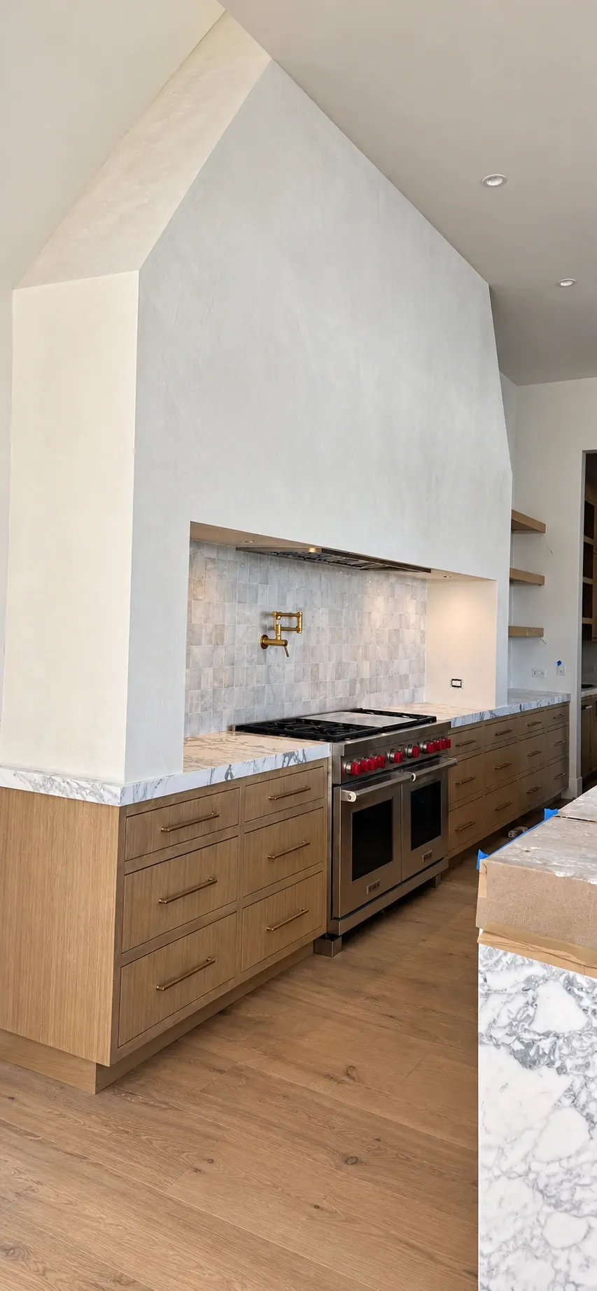 Modern kitchen with wood cabinetry, stainless steel range, and white shiplap hood